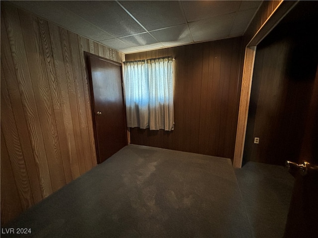 carpeted empty room with wood walls