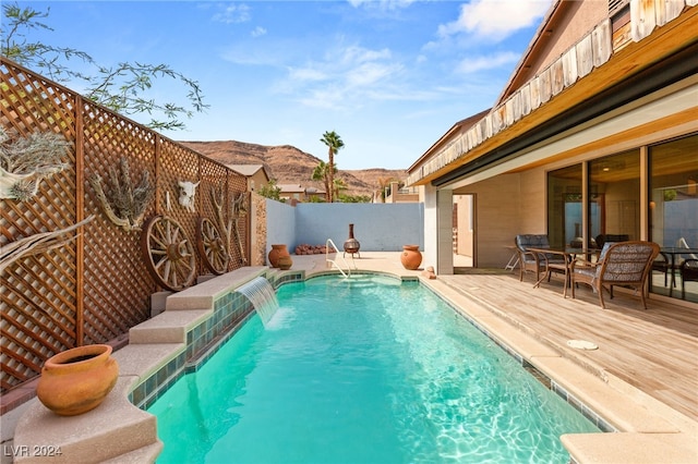 view of pool with pool water feature and a deck with mountain view