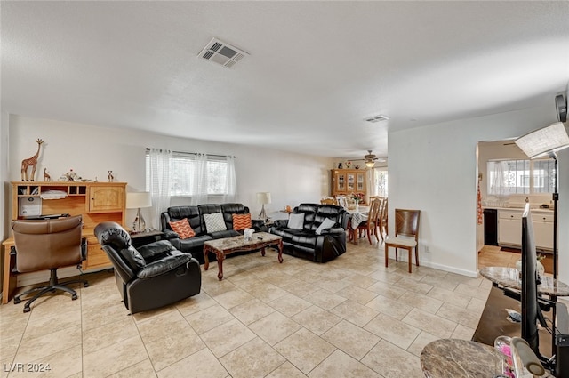 tiled living room featuring ceiling fan and plenty of natural light