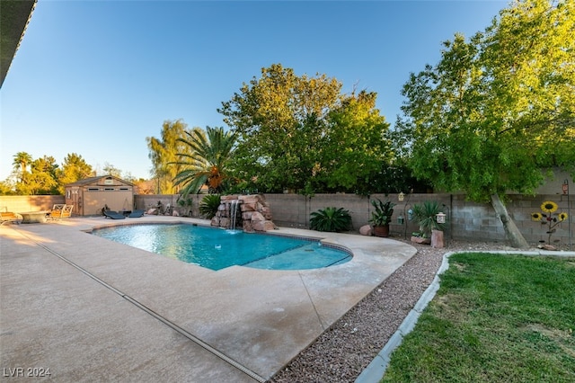 view of swimming pool with a patio area, a storage unit, and pool water feature