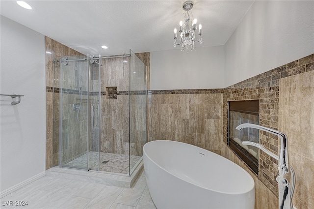 bathroom featuring a chandelier, tile walls, plus walk in shower, and a textured ceiling