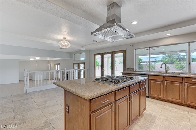 kitchen featuring a center island, island range hood, appliances with stainless steel finishes, light tile patterned floors, and a textured ceiling