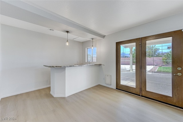 kitchen featuring kitchen peninsula, hanging light fixtures, light stone countertops, and light wood-type flooring