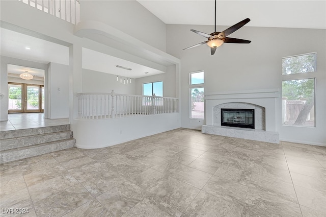 unfurnished living room featuring ceiling fan, a fireplace, high vaulted ceiling, and a wealth of natural light