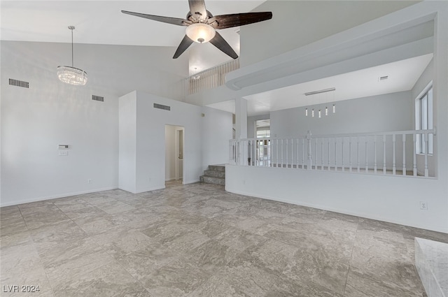 empty room featuring ceiling fan with notable chandelier and high vaulted ceiling