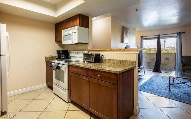 kitchen featuring light tile patterned flooring, white appliances, light stone countertops, and kitchen peninsula