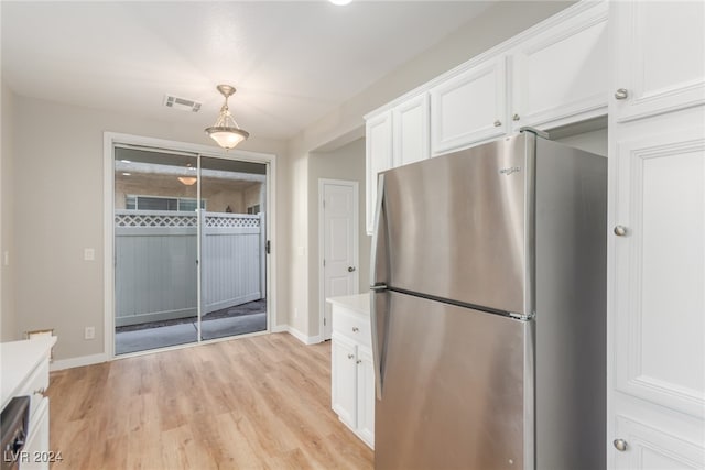 kitchen featuring stainless steel refrigerator, white cabinetry, light hardwood / wood-style floors, and decorative light fixtures