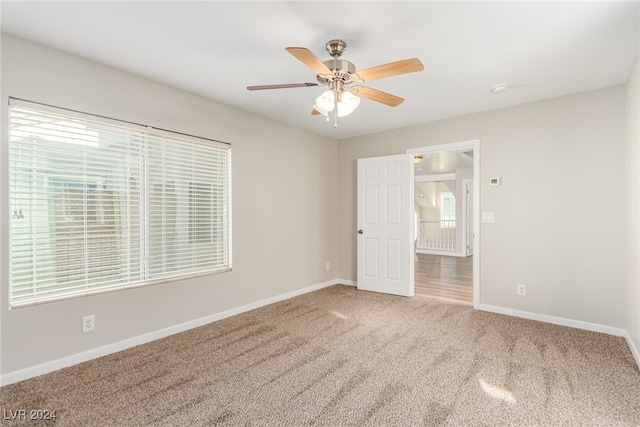 carpeted empty room featuring ceiling fan and a healthy amount of sunlight