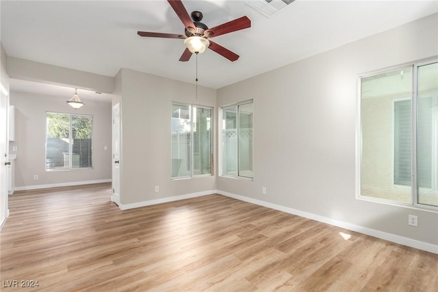 empty room with ceiling fan and light hardwood / wood-style flooring