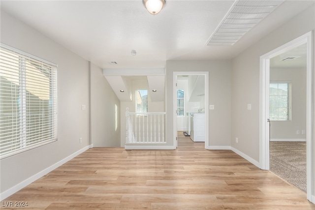 interior space featuring light hardwood / wood-style floors, washer / dryer, and a wealth of natural light