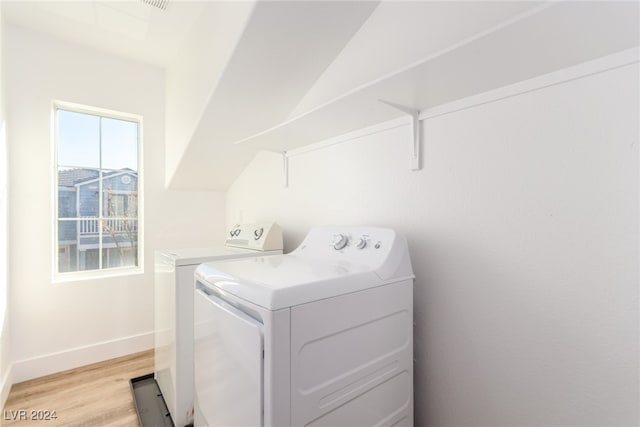 clothes washing area with light hardwood / wood-style flooring and washer and clothes dryer