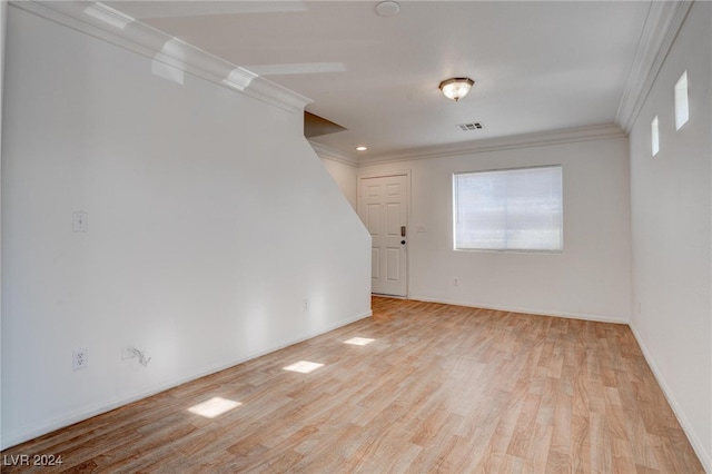 spare room featuring crown molding and light hardwood / wood-style floors