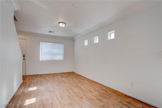 empty room featuring light wood-type flooring, ornamental molding, and a wealth of natural light