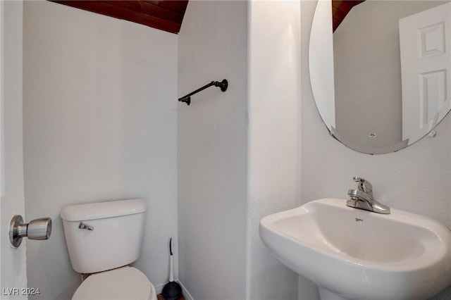 bathroom with sink, vaulted ceiling, and toilet