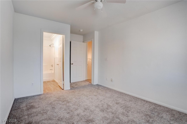 unfurnished bedroom featuring ceiling fan, light colored carpet, and ensuite bath