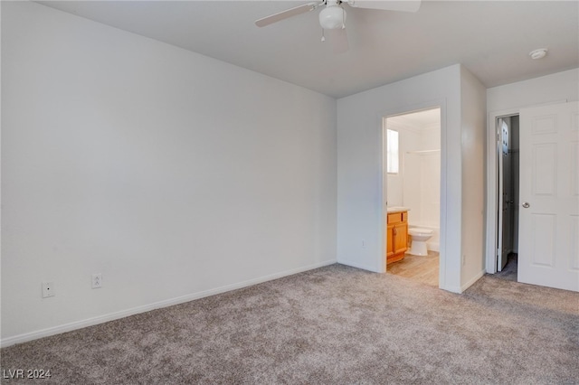 unfurnished bedroom with light colored carpet, ensuite bathroom, and ceiling fan