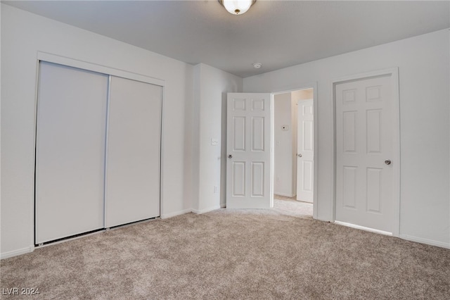 unfurnished bedroom featuring light carpet and a closet