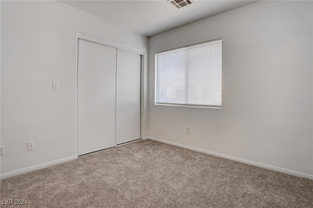 unfurnished bedroom featuring light colored carpet and a closet