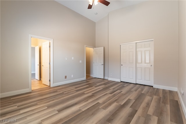 unfurnished bedroom with ceiling fan, light hardwood / wood-style flooring, a closet, and high vaulted ceiling