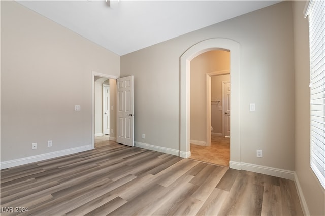 unfurnished bedroom featuring hardwood / wood-style flooring and vaulted ceiling