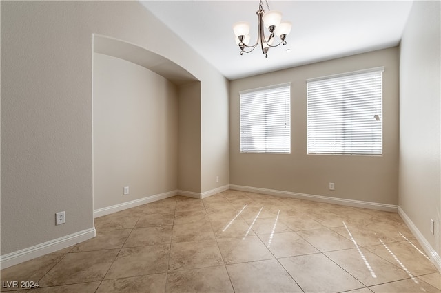 tiled empty room featuring a chandelier