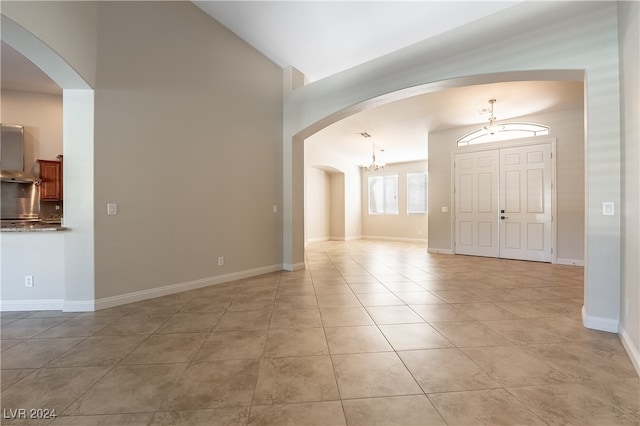 foyer with lofted ceiling, a notable chandelier, and light tile patterned floors