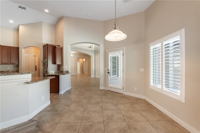 interior space featuring plenty of natural light, dark stone countertops, high vaulted ceiling, and decorative light fixtures