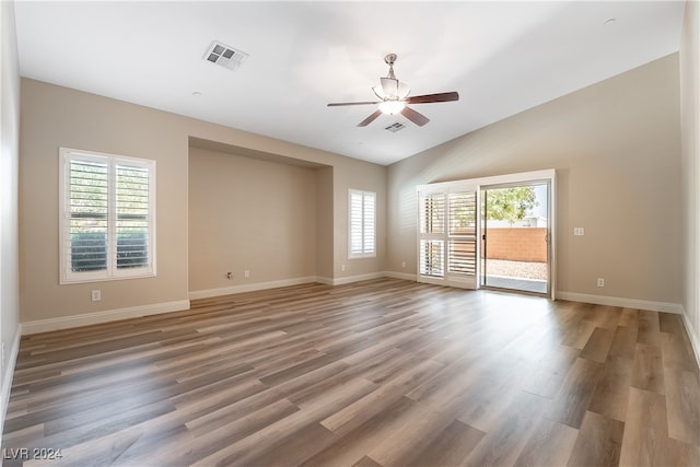 empty room featuring vaulted ceiling, hardwood / wood-style floors, and a healthy amount of sunlight