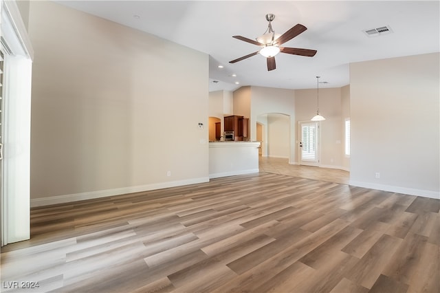 unfurnished living room featuring high vaulted ceiling, light hardwood / wood-style flooring, and ceiling fan