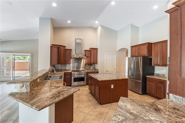 kitchen with high vaulted ceiling, sink, kitchen peninsula, wall chimney range hood, and appliances with stainless steel finishes