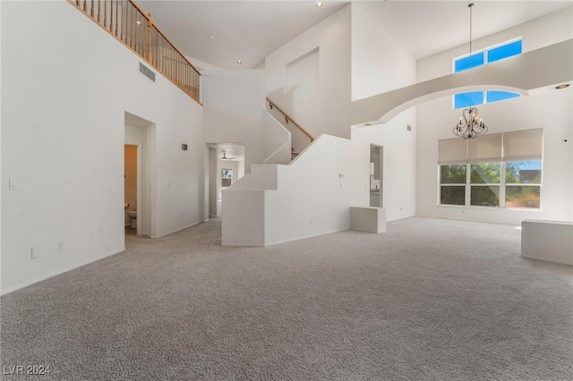 unfurnished living room with a notable chandelier, a high ceiling, and carpet