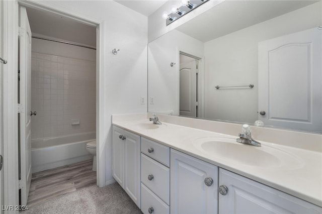 full bathroom with hardwood / wood-style floors, vanity, toilet, and tiled shower / bath combo