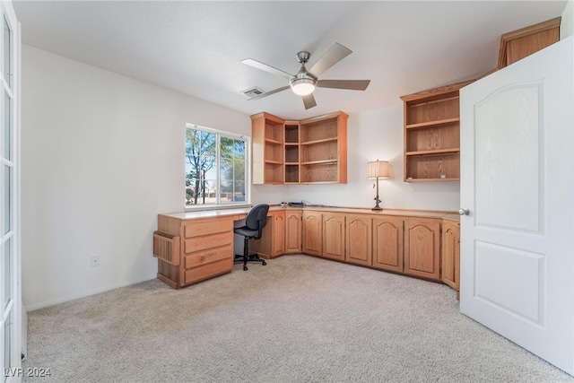 home office featuring ceiling fan, light colored carpet, and built in desk