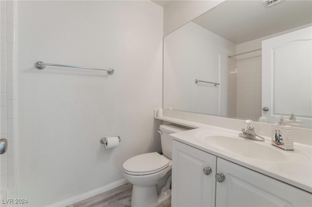 bathroom with a shower, hardwood / wood-style floors, vanity, and toilet