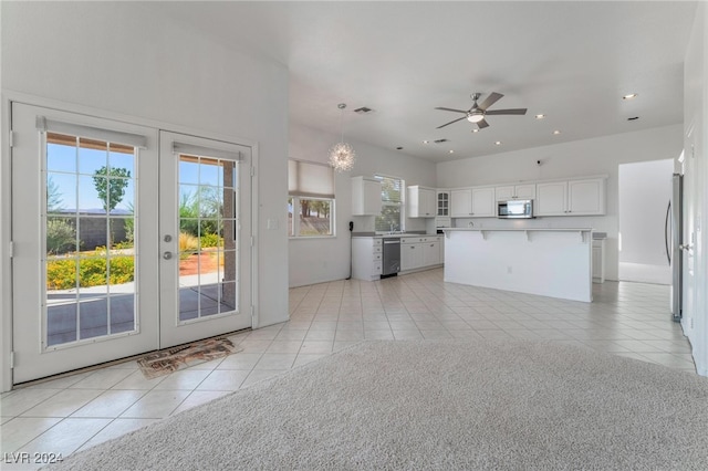 kitchen featuring white cabinets, light tile patterned floors, a kitchen island, decorative light fixtures, and appliances with stainless steel finishes