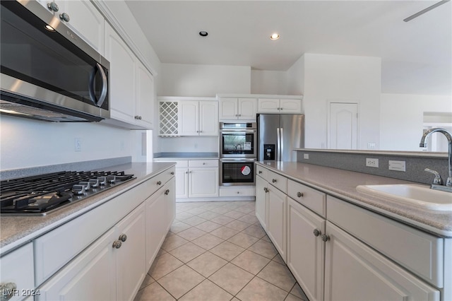 kitchen with appliances with stainless steel finishes, white cabinetry, sink, and light tile patterned floors