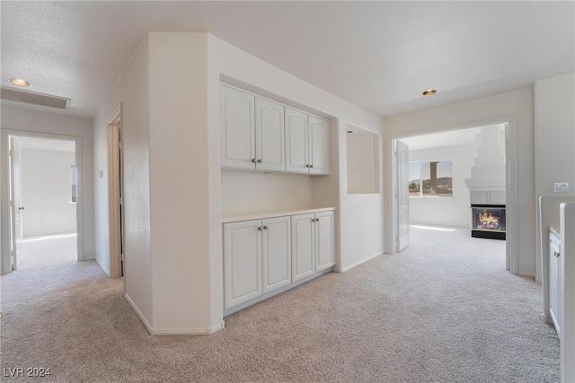 hall with light colored carpet and a textured ceiling