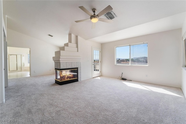 unfurnished living room featuring light carpet, ceiling fan, vaulted ceiling, and a tiled fireplace