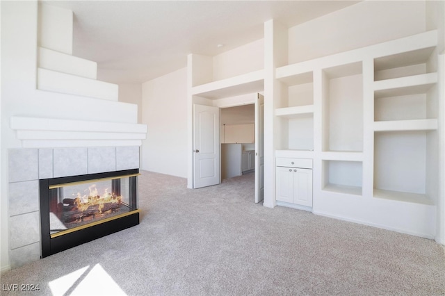 unfurnished living room with built in features, a multi sided fireplace, and light carpet