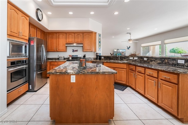 kitchen featuring stainless steel appliances, dark stone counters, a kitchen island, and light tile patterned floors