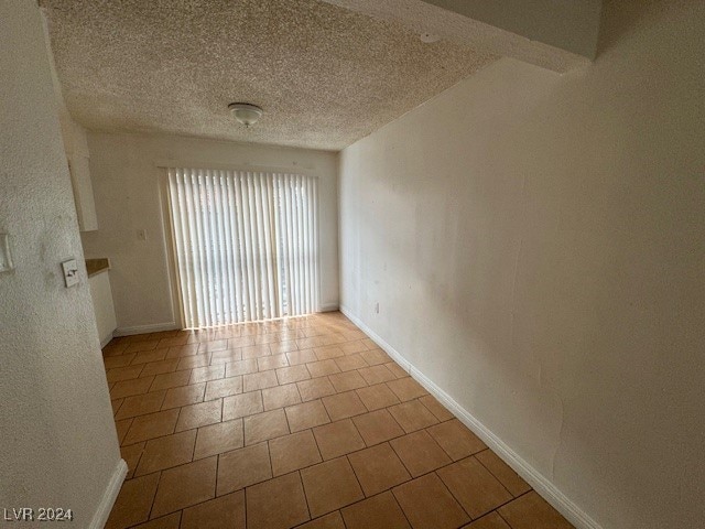 tiled empty room with a textured ceiling