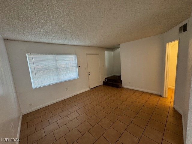 empty room featuring light tile patterned floors and a textured ceiling