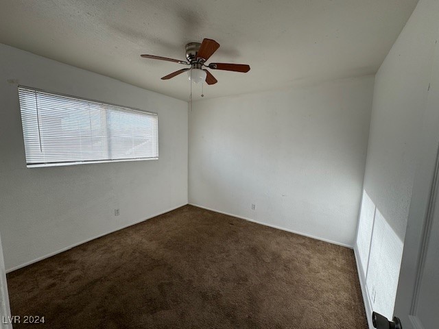 spare room with dark carpet and ceiling fan