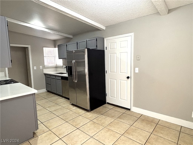 kitchen with a textured ceiling, stainless steel appliances, light tile patterned floors, and gray cabinetry