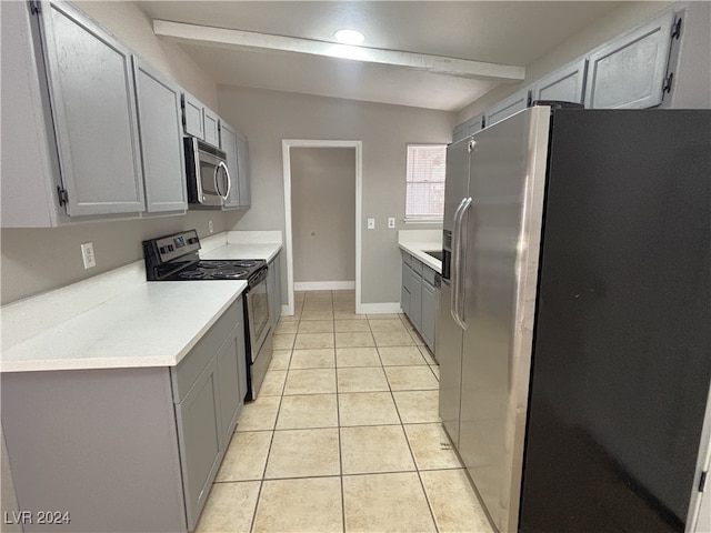 kitchen featuring gray cabinetry, appliances with stainless steel finishes, light tile patterned floors, and vaulted ceiling