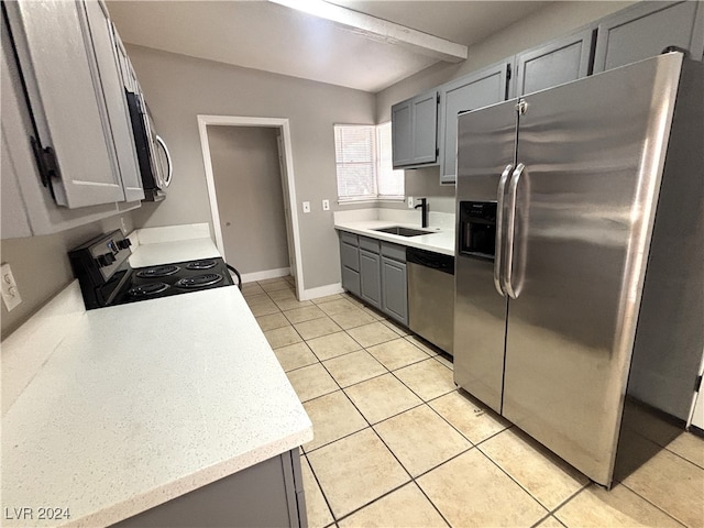 kitchen with light tile patterned flooring, gray cabinets, vaulted ceiling, sink, and stainless steel appliances