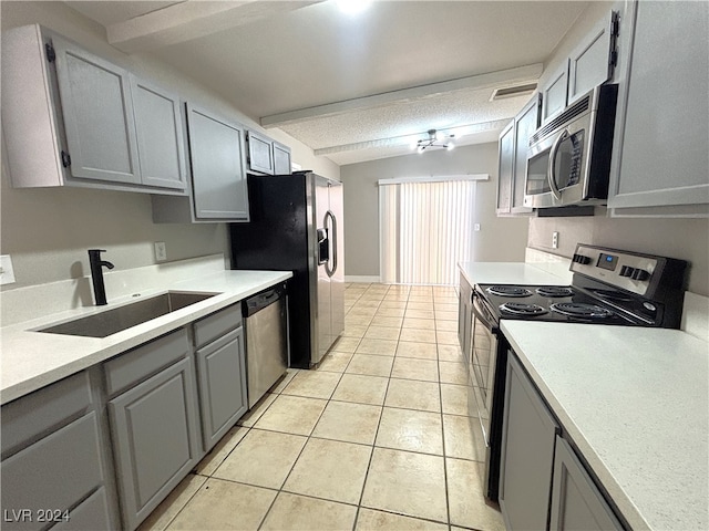 kitchen featuring light tile patterned flooring, stainless steel appliances, sink, and gray cabinetry