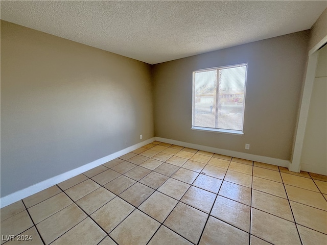 tiled spare room featuring a textured ceiling