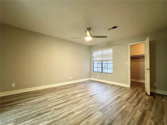 unfurnished bedroom with a closet, hardwood / wood-style floors, a walk in closet, and ceiling fan