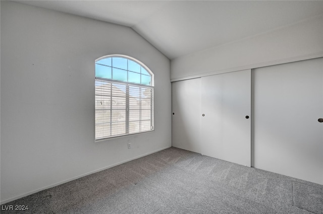 unfurnished bedroom featuring lofted ceiling, a closet, and carpet flooring